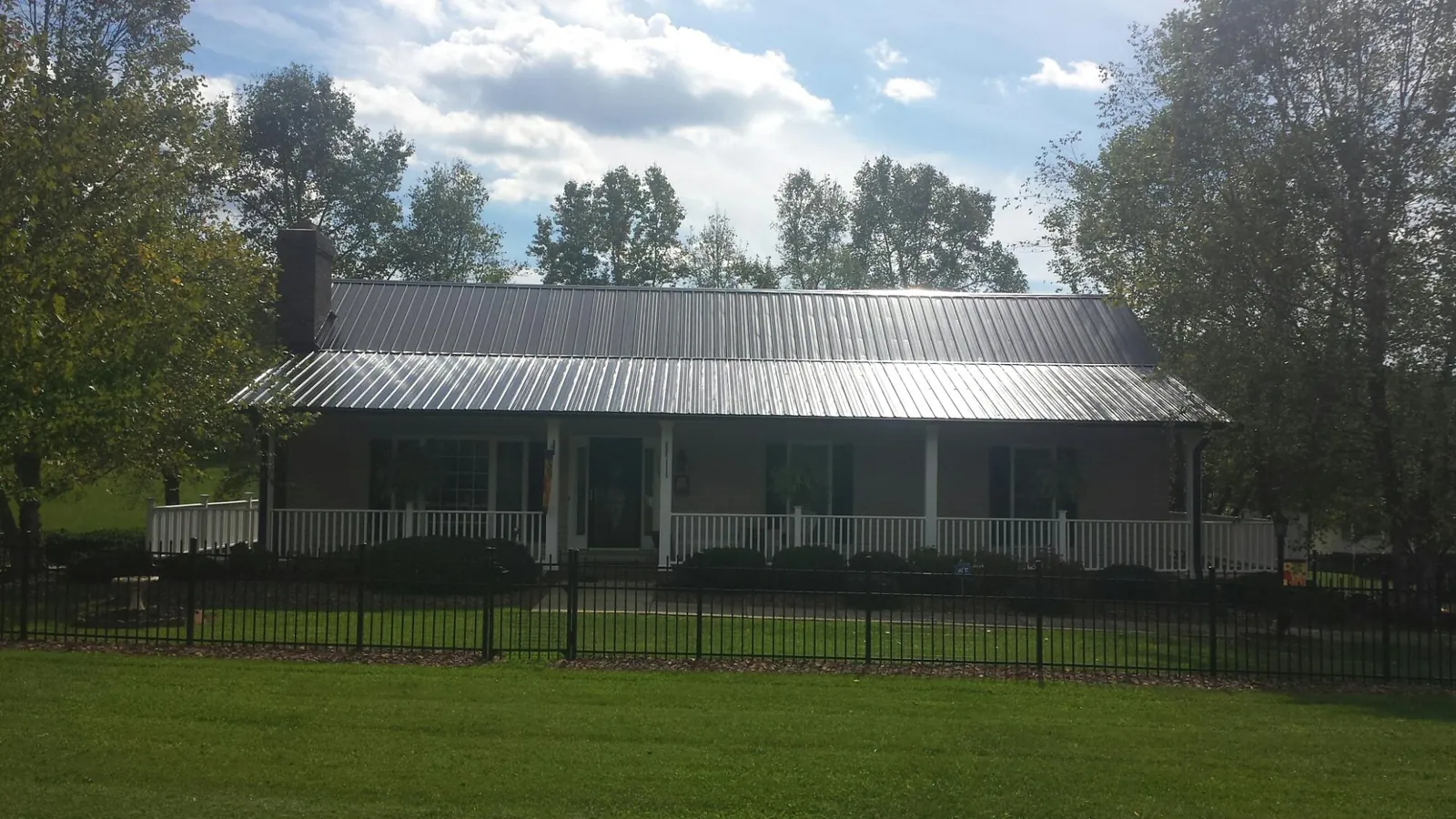 Gray metal roof on a brick ranch with a full width front porch — Gutter Guard Installation work by our crew in Deerfield Beach