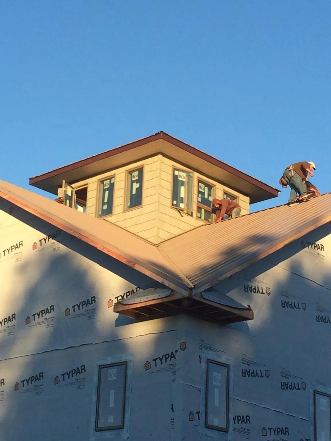 Roofers working around a rooftop cupola on a new metal roof at sunset — Roof Waterproofing in Deerfield Beach by Roofing Brothers